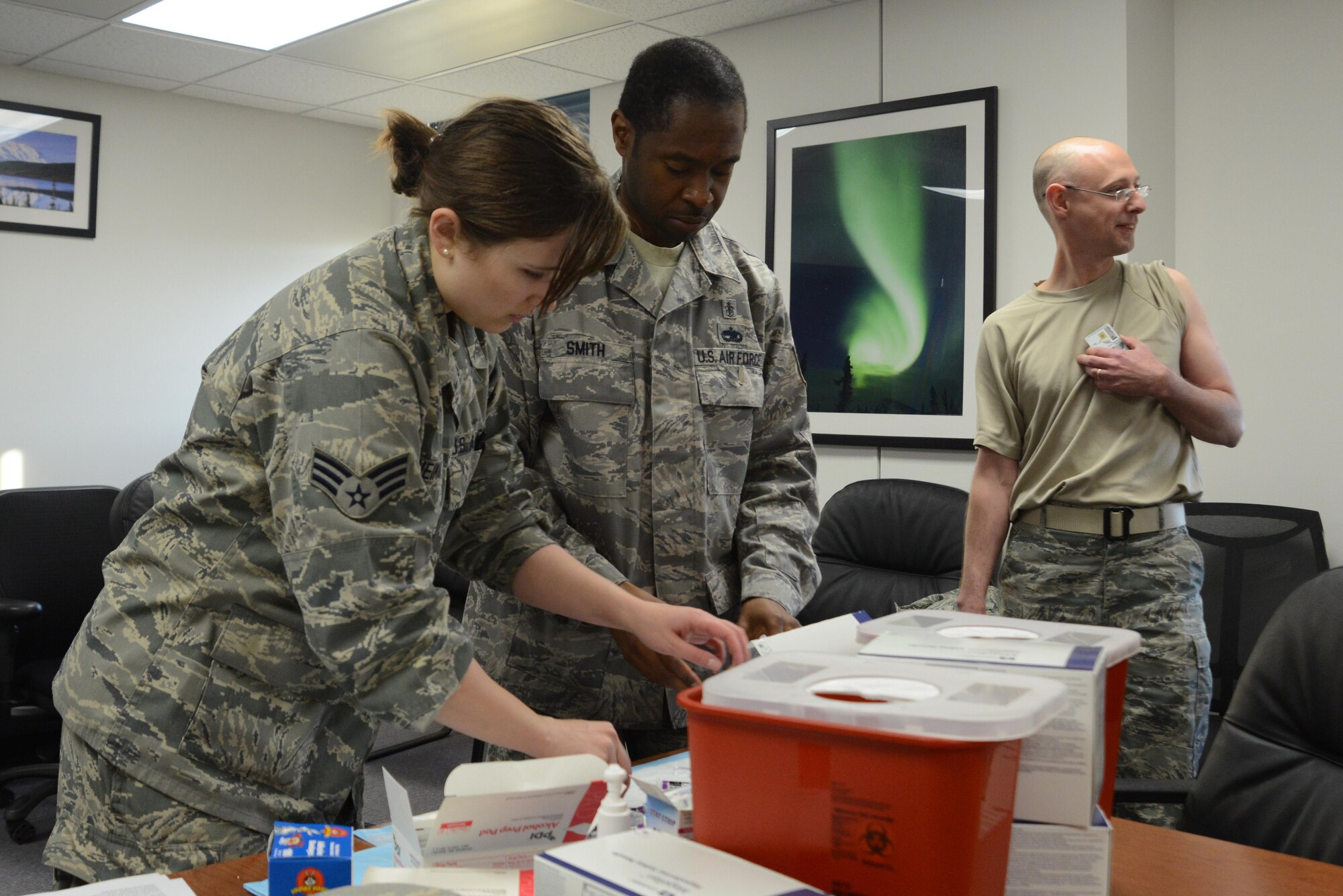 Senior Airman Casie Neiman and Tech. Sgt. Stenneth Smith, with the 673d Medical Operational Support Allergy and Immunizations clinic, prepare all the necessary equipment for a flu vaccination line at the People Center at Joint Base Elmendorf-Richardson, Alaska, Oct. 5, 2016. To speed the flu line’s process, the clinic recommended having common access cards and chosen arms ready.
