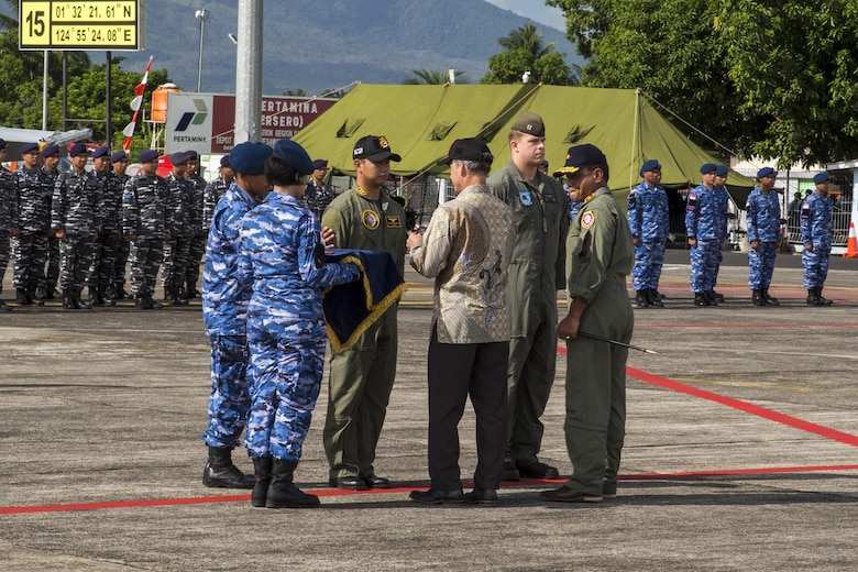 U.S. Marine Corps Capt. Bryan Boer, a pilot with All-Weather Fighter Attack Squadron (VMFA (AW)) 225, and an Indonesian Air Force pilot, participate in a traditional patch exchange during the Cope West 17 opening ceremony at Sam Ratulangi International Airport, Indonesia, Nov. 1, 2016. The Charge de Affairs, Brian McFeeters, replaces the pilots; patches with the Cope West patch, symbolizing the commencement of the exercise. (U.S. Marine Corps photo by Cpl. Aaron Henson)