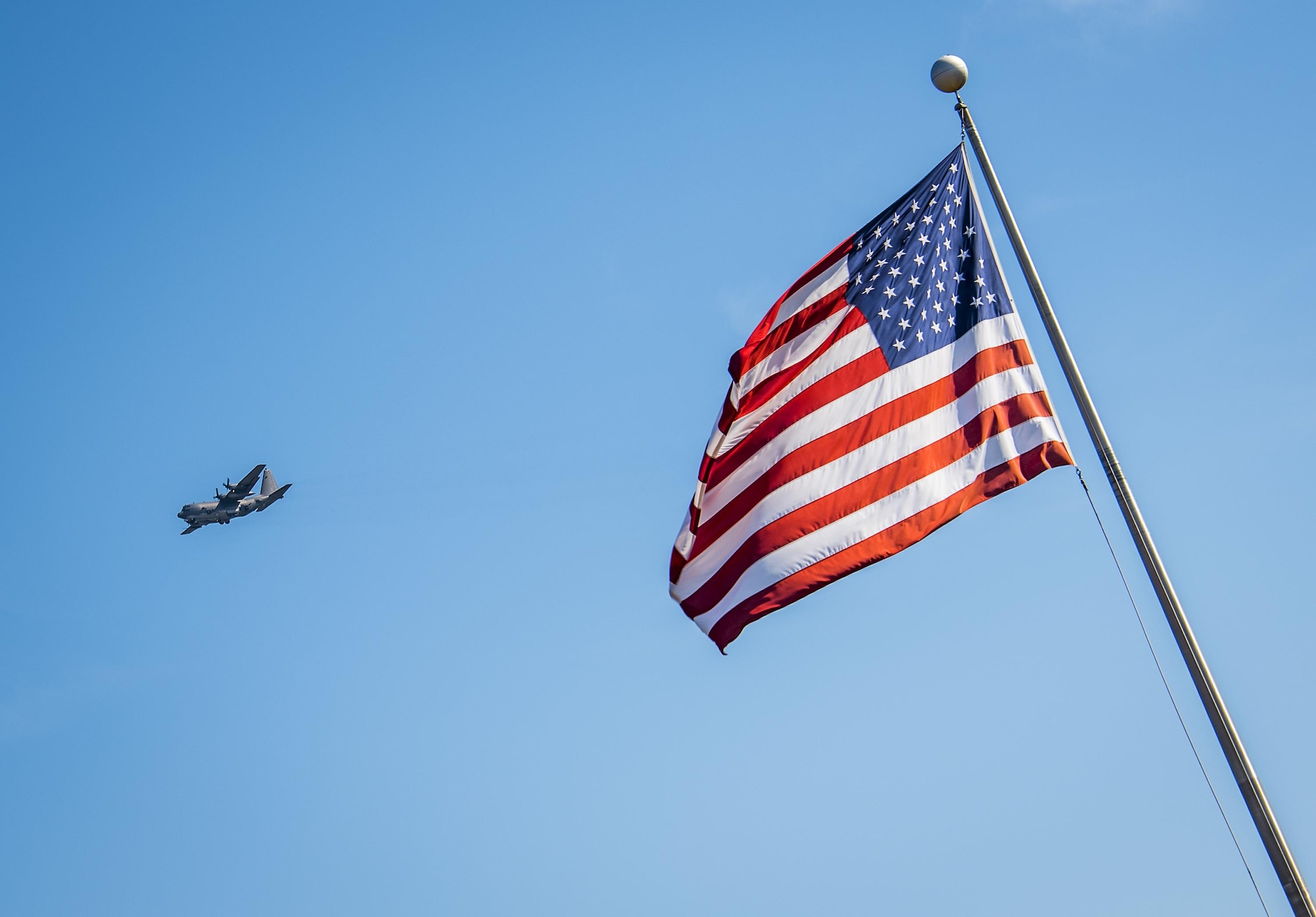 A C-130 flies by the American flag in front of the 96th Test Wing headquarters building at Eglin Air Force Base, Fla., Nov. 1.  (U.S. Air Force photo/Samuel King Jr.)