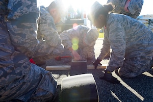 Members of the 633rd Civil Engineer Squadron participate at an electrical power production station during a Prime Base Engineering Emergency Force training at Joint Base Langley-Eustis, Va., Oct. 25, 2016. At this station, which was one of 12, they punched out and reeved nylon purchase tape through a tape connector. (U.S. Air Force photo by Senior Airman Kimberly Nagle) 