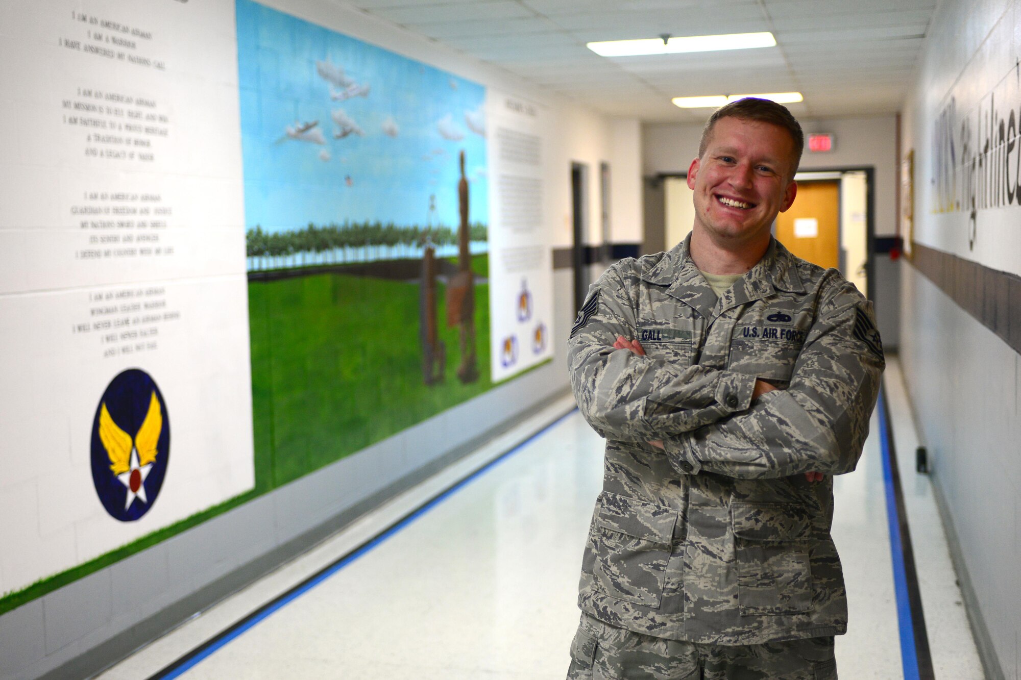 Tech Sgt. Adam Gall, a program manager with the 55th Aircraft Maintenance Squadron at Offutt Air Force Base, Neb., stands in front of a mural he painted in the Bennie Davis Maintenance Facility Oct. 12, 2016. Gall bookended a scene involving aircraft maintained by the 55th Wing with the text of the Airman’s Creed and the Maintenance Creed. (U.S. Air Force photo/Senior Airman Rachel Hammes)