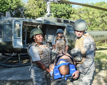 Tech. Sgt. Angel Urgilez, student and paramedic from Hurbert Field Air Force Base, Florida, and Staff Sergeants Jesse Curtis and Cassandra Bayerl, students and paramedics from the 59th Medical Wing, practice offloading a simulated patient during the Paramedic Recertification Course on Joint Base San Antonio-Lackland, Texas, Sept. 19, 2016. (U.S. Air Force photo/Staff Sgt. Michael Ellis)