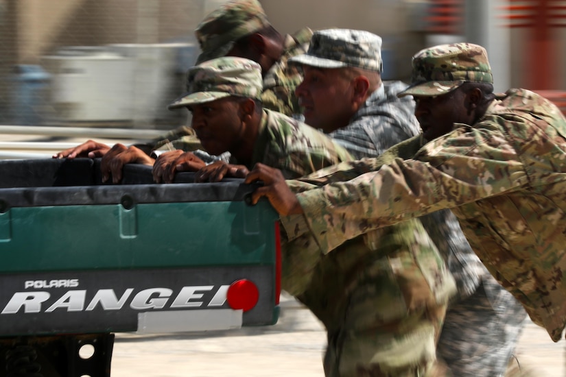 Soldiers push a golf cart around a softball field as part of the NCO Week games at Camp Arifjan, Kuwait, Oct. 14, 2016. The subordinate units in the 160th Signal Brigade from Afghanistan and Qatar fielded teams to compete in the games. (U.S. Army photo by Sgt. Brandon Hubbard, USARCENT Public Affairs)