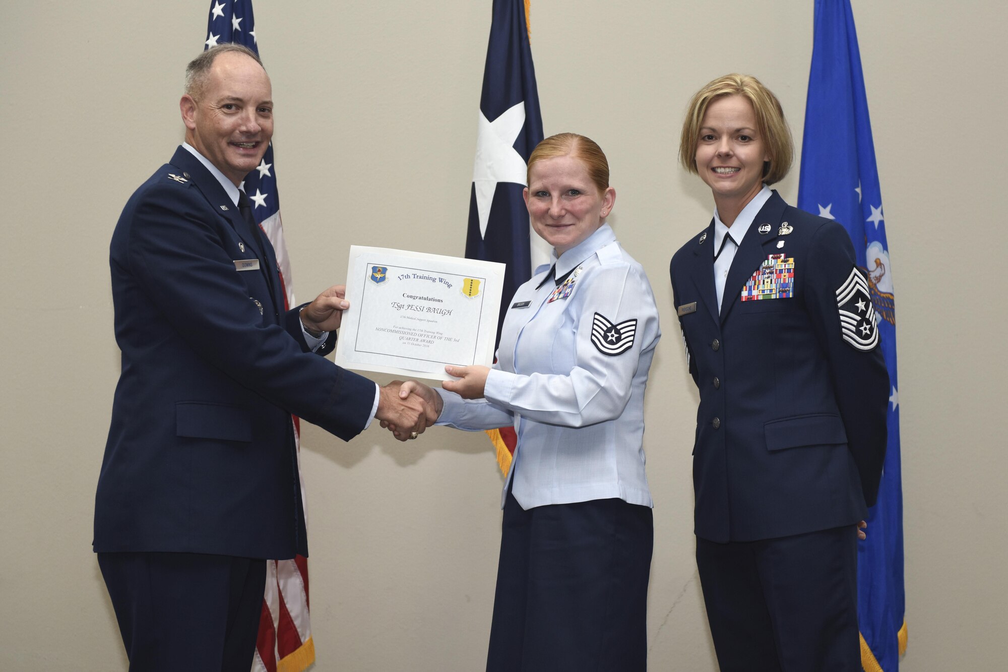 U.S. Air Force Col. Michael Downs, 17th Training Wing Commander, and Chief Master Sgt. Bobbie Riensche, 17th TRW Command Chief, present the NCO of the Quarter award to Tech. Sgt. Jessi Baugh, 17th Medical Support Squadron, during the wing quarterly awards ceremony at the Event Center on Goodfellow Air Force Base, Texas, Oct. 31, 2016. (U.S. Air Force photo by Airman 1st Class Chase Sousa/Released)