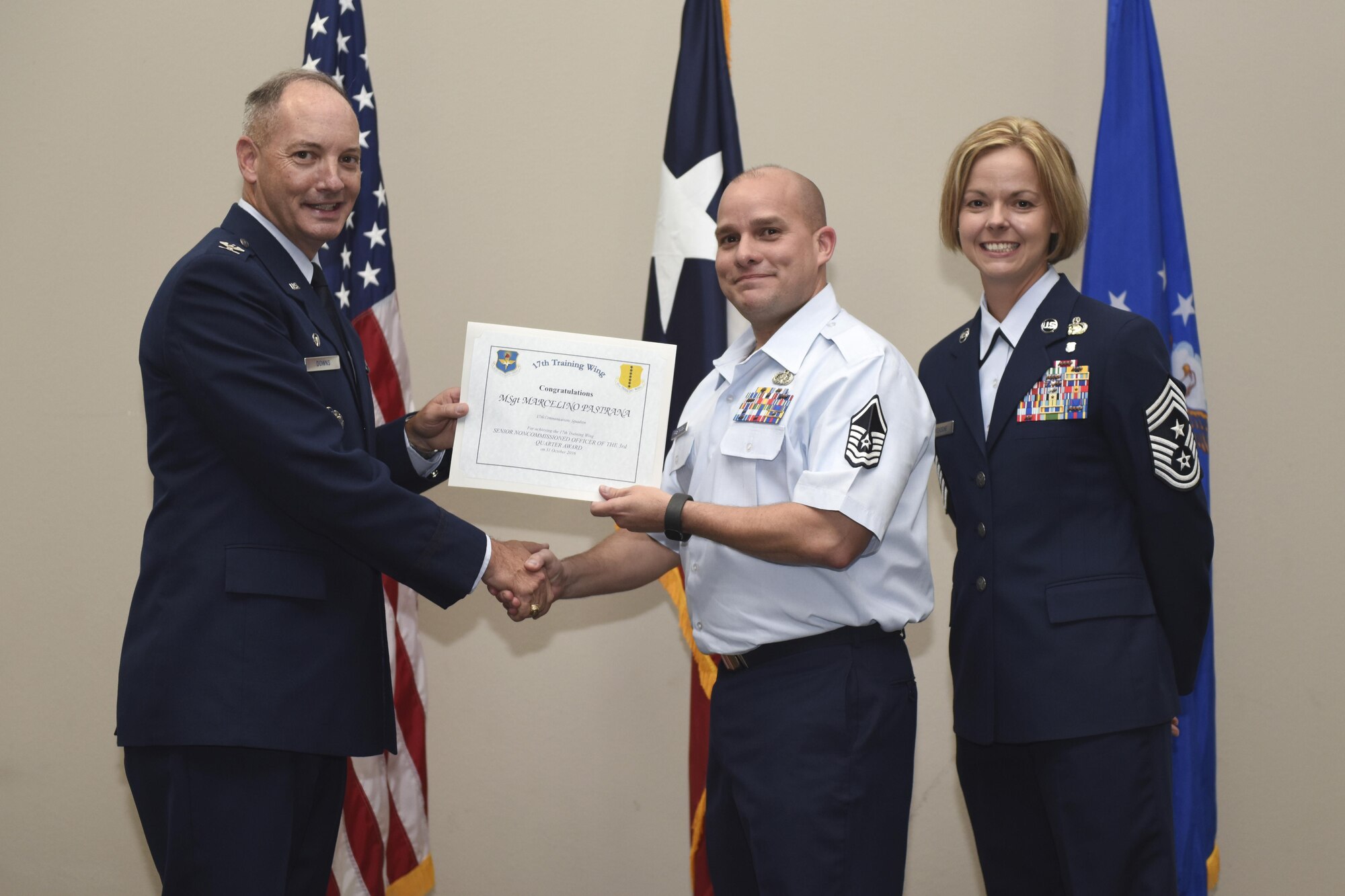 U.S. Air Force Col. Michael Downs, 17th Training Wing Commander, and Chief Master Sgt. Bobbie Riensche, 17th TRW Command Chief, present the Senior NCO of the Quarter award to Master Sgt. Marcelino Pastrana, 17th Contracting Squadron, during the wing quarterly awards ceremony at the Event Center on Goodfellow Air Force Base, Texas, Oct. 31, 2016. (U.S. Air Force photo by Airman 1st Class Chase Sousa/Released)
