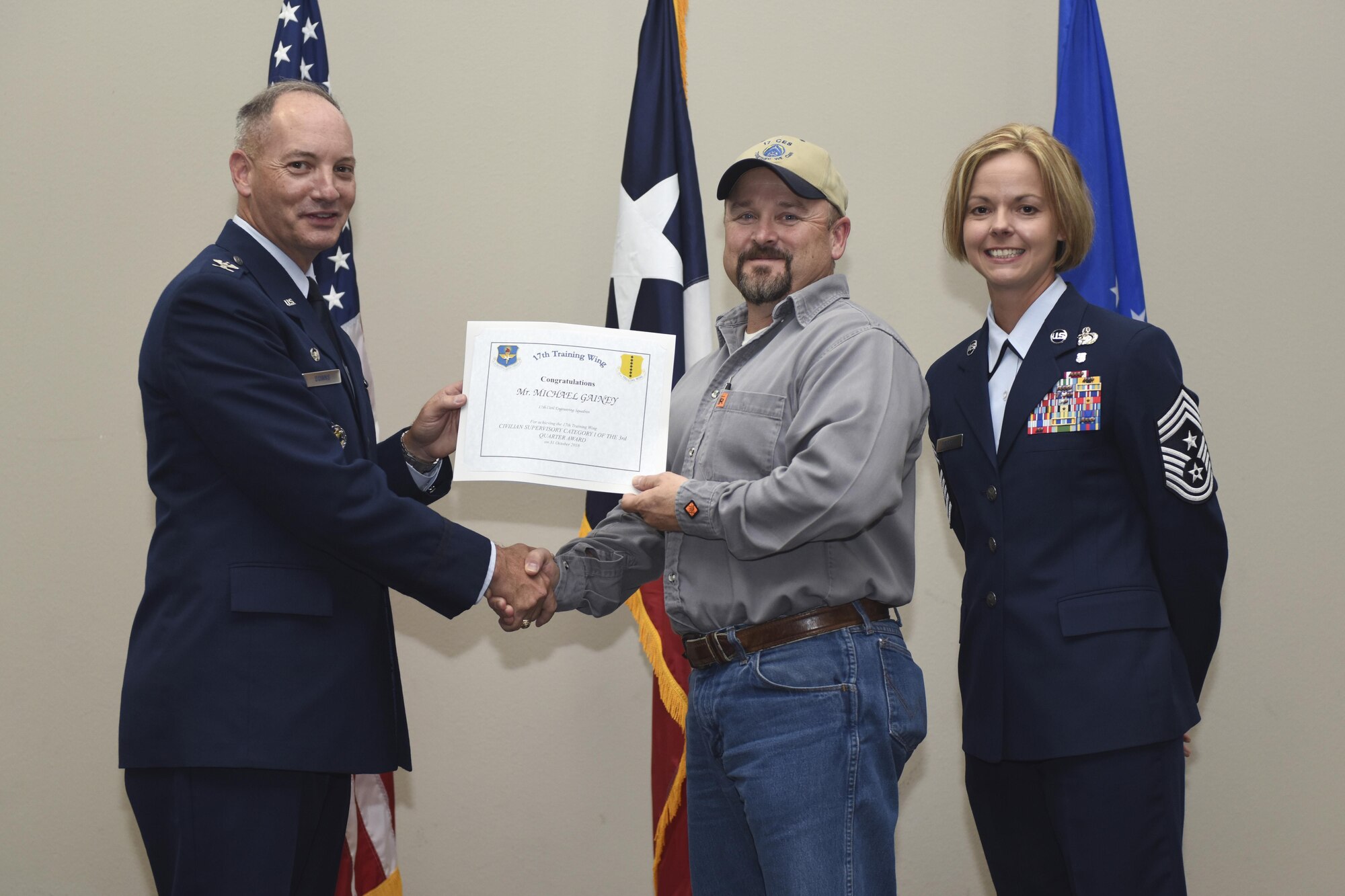 U.S. Air Force Col. Michael Downs, 17th Training Wing Commander, and Chief Master Sgt. Bobbie Riensche, 17th TRW Command Chief, present the Civilian Category II Non-Supervisory of the Quarter Christopher Hill, 17th Training Support Squadron, during the wing quarterly awards ceremony at the Event Center on Goodfellow Air Force Base, Texas, Oct. 31, 2016. (U.S. Air Force photo by Airman 1st Class Chase Sousa/Released)