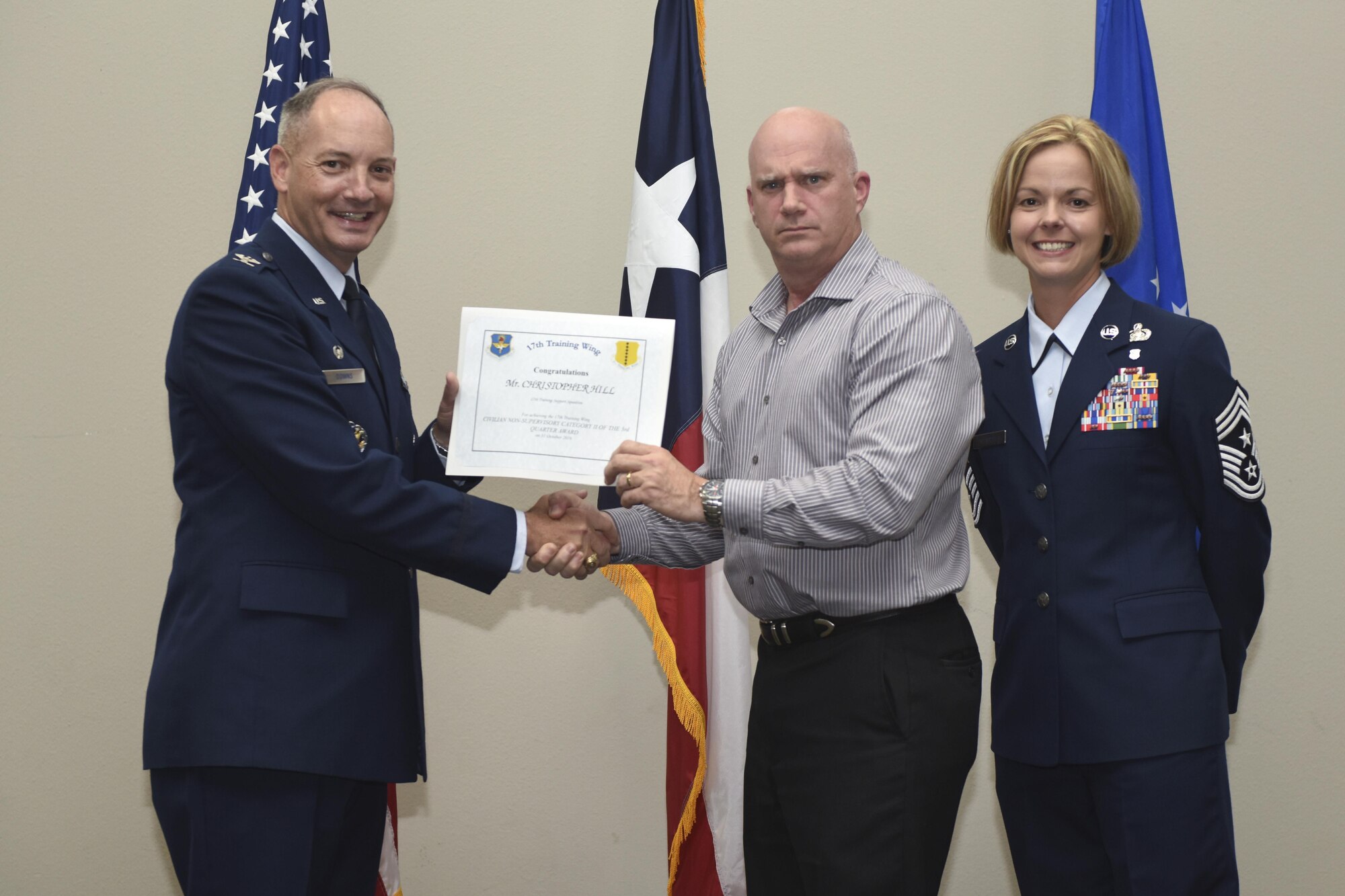 U.S. Air Force Col. Michael Downs, 17th Training Wing Commander, and Chief Master Sgt. Bobbie Riensche, 17th TRW Command Chief, present the Civilian Category I Supervisory of the Quarter to Michael Gainey, 17th Civil Engineer Squadron, during the wing quarterly awards ceremony at the Event Center on Goodfellow Air Force Base, Texas, Oct. 31, 2016. (U.S. Air Force photo by Airman 1st Class Chase Sousa/Released)