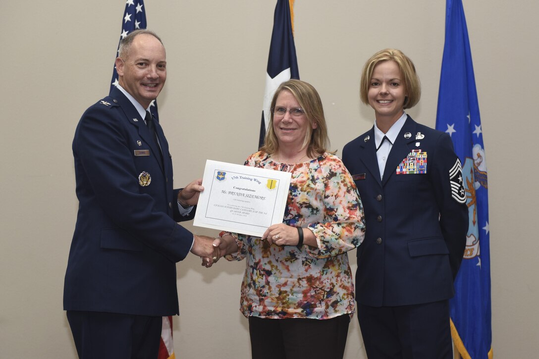 U.S. Air Force Col. Michael Downs, 17th Training Wing Commander, and Chief Master Sgt. Bobbie Riensche, 17th TRW Command Chief, present the Civilian Category II Supervisory of the Quarter to Brenda Sizemore, 17th Contracting Squadron, during the wing quarterly awards ceremony at the Event Center on Goodfellow Air Force Base, Texas, Oct. 31, 2016. (U.S. Air Force photo by Airman 1st Class Chase Sousa/Released)