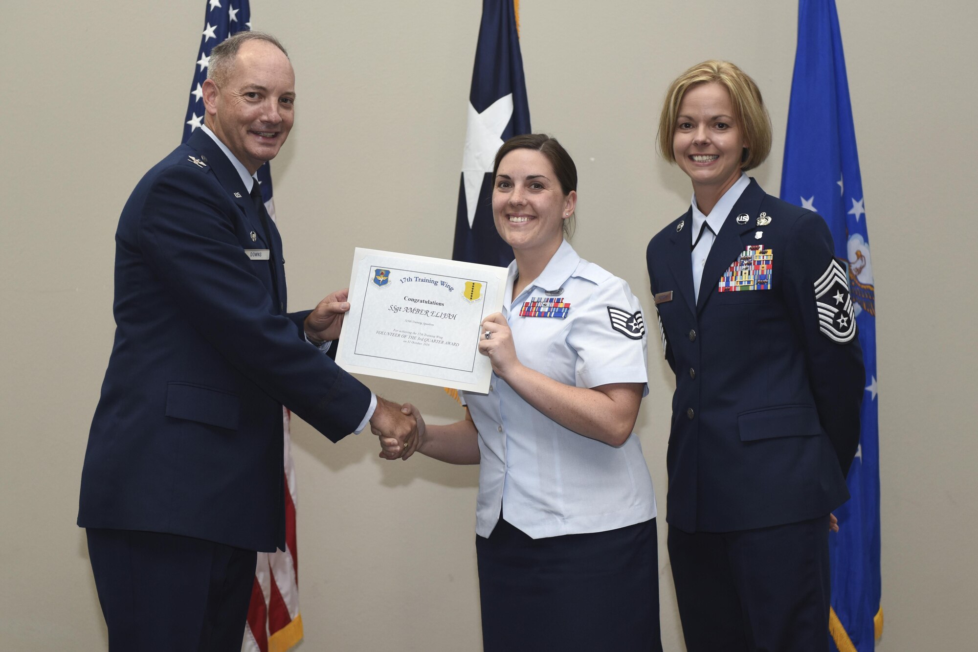 U.S. Air Force Col. Michael Downs, 17th Training Wing Commander, and Chief Master Sgt. Bobbie Riensche, 17th TRW Command Chief, present the Volunteer of the Quarter to Staff Sgt. Amber Elijah, 315th Training Squadron, during the wing quarterly awards ceremony at the Event Center on Goodfellow Air Force Base, Texas, Oct. 31, 2016. (U.S. Air Force photo by Airman 1st Class Chase Sousa/Released)