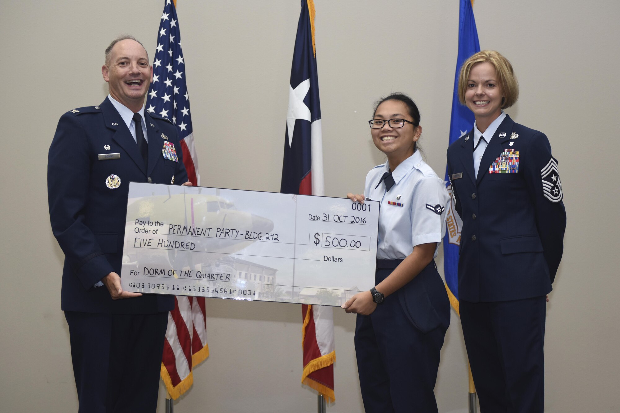 U.S. Air Force Col. Michael Downs, 17th Training Wing Commander, and Chief Master Sgt. Bobbie Riensche, 17th TRW Command Chief, present the Permanent Party Dorm of the Quarter to a Bldg. 242 resident during the wing quarterly awards ceremony at the Event Center on Goodfellow Air Force Base, Texas, Oct. 31, 2016. The money awarded is used to improve the building as well as raise the morale of residents. (U.S. Air Force photo by Airman 1st Class Chase Sousa/Released)