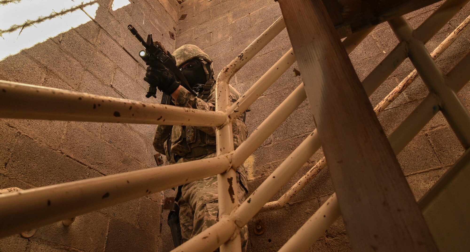 An Airman assigned to the 799th Security Forces Squadron guards the stairs as a fire team attempts to clear a building during the field training exercise of a Fundamentals of Proficiency Fire and Close Quarters Battle course, Oct. 21, 2016, at Range 63C, Silver Flag Alpha, Nev. Volunteers from Nellis and Creech Air Force Bases acted as locals and opposing forces in a mock-deployment environment for the exercise. (U.S. Air Force photo by Airman 1st Class James Thompson)