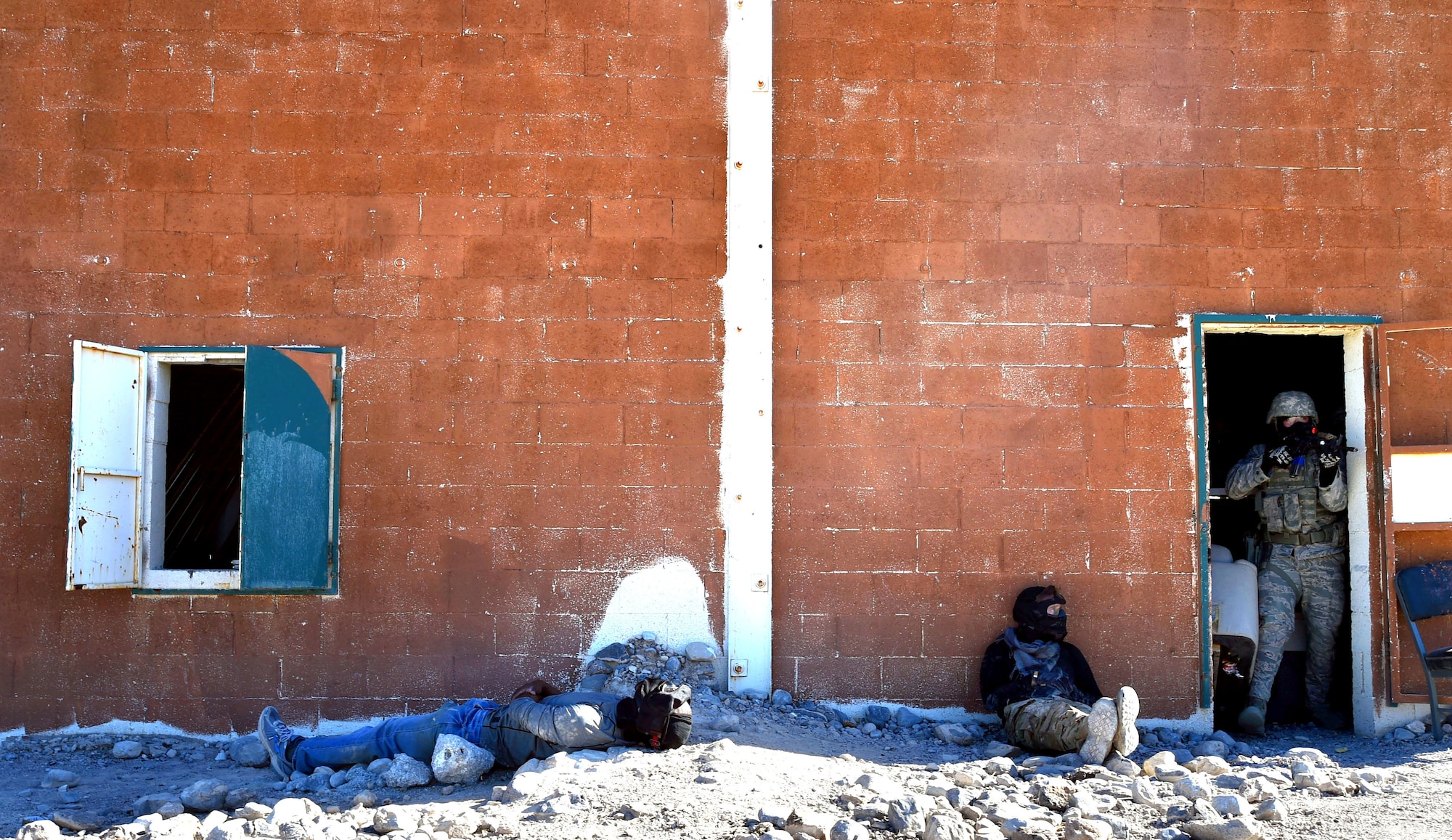 Airmen assigned to the 799th Security Forces Squadron prepare to exit a cleared building during the field training exercise of a Fundamentals of Proficiency Fire and Close Quarters Battle course, Oct. 21, 2016, at Range 63C, Silver Flag Alpha, Nev. The exercise consisted of a mock-deployment environment with volunteers acting as locals and opposing forces. (U.S. Air Force photo by Airman 1st Class James Thompson) 