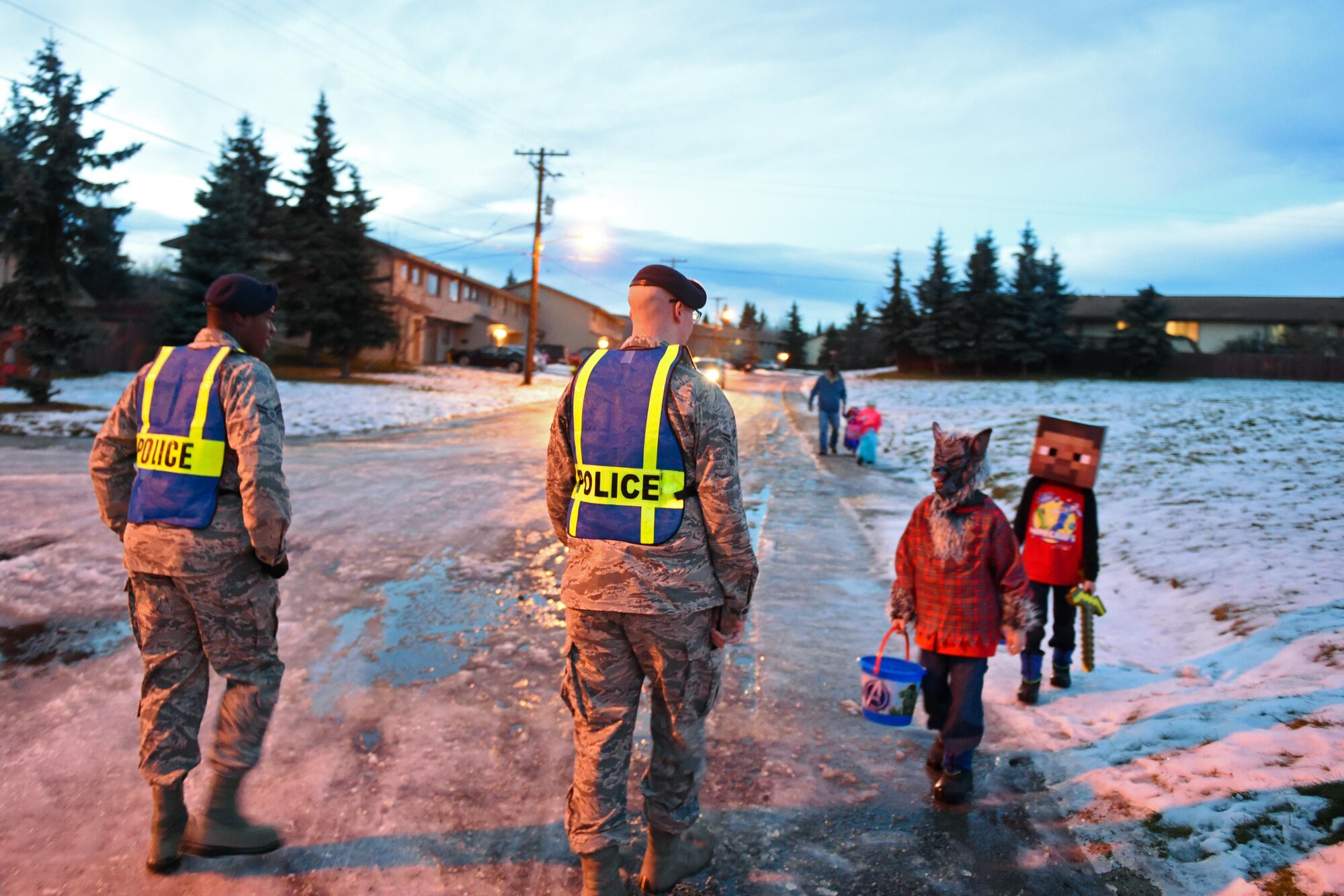 Airman 1st Class Davis Lavance and Airman 1st Class Justin Rippentrop, entry controllers with the 673d Security Forces Squadron, assist trick-or-treaters as they cross the street at the Chugach housing community at Joint Base Elmendorf-Richardson, Oct. 31, 2016. Members of the 673d SFS participated in Pumpkin Patrol, an annual event which provides an increased police presence throughout base housing – affording candy enthusiasts a secure environment to trick-or-treat. 