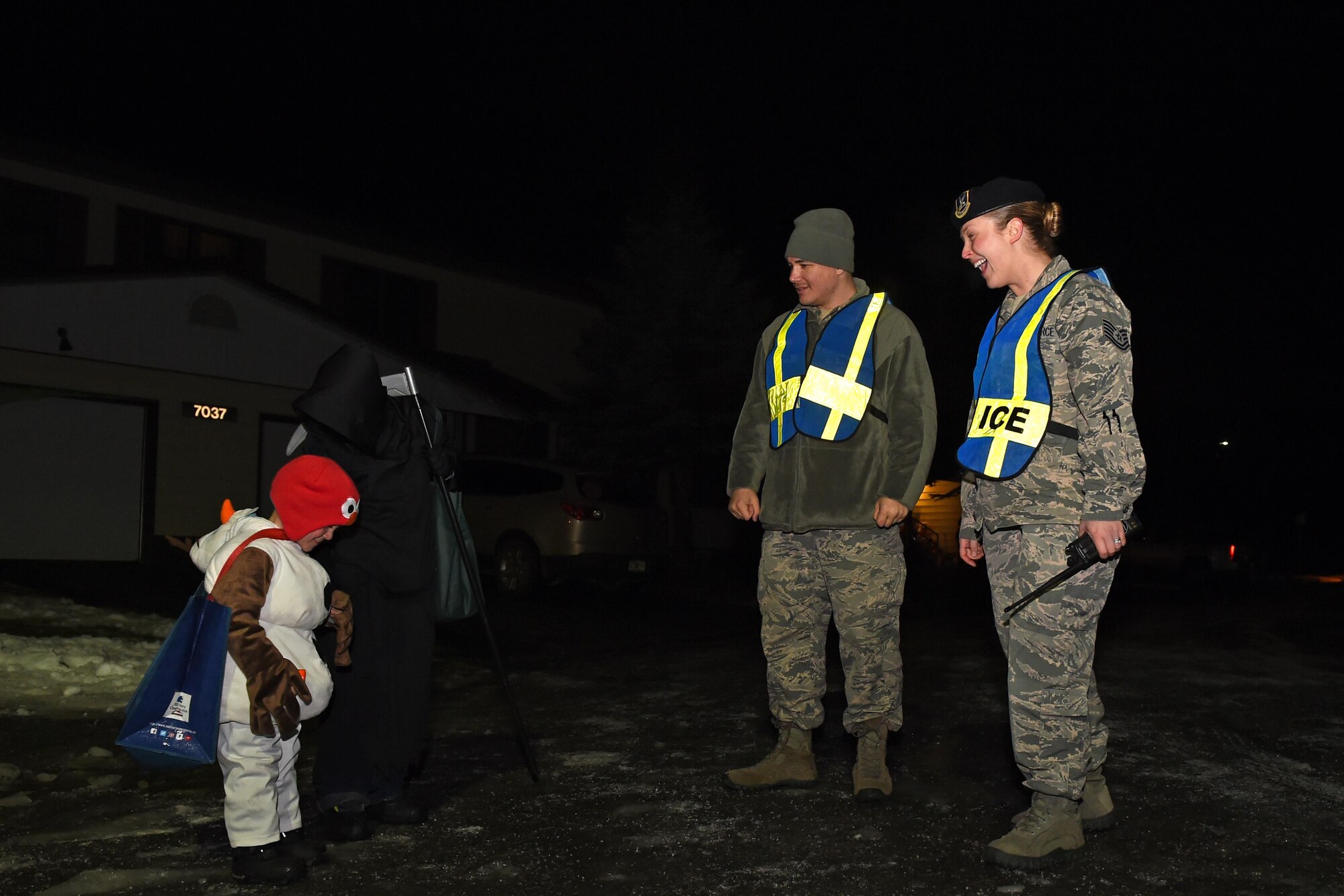 Staff Sgt. Jacob Mcquillen, 673d Security Forces Squadron patrolman, and Tech. Sgt. Sarah Qualle, 673d SFS noncommissioned officer in charge of police services, meet with trick-or-treaters, at the Cherry Hill housing community, Oct. 31, 2016. Members of the 673d SFS participated in Pumpkin Patrol, an annual event which provides an increased police presence throughout base housing – affording candy enthusiasts a secure environment to trick-or-treat. 