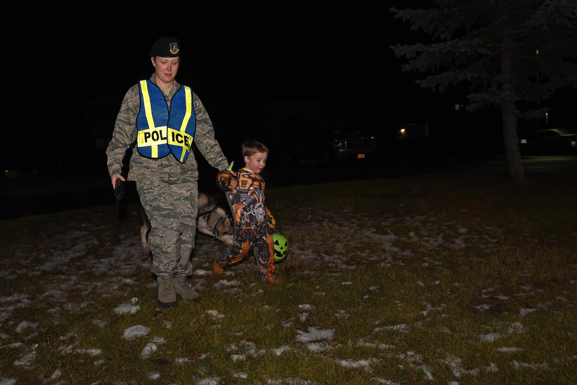 Technical Sgt. Sarah Qualle, 673d SFS noncommissioned officer in charge of police services, walks Ben Bauer, 4, across an icy patch of grass, Oct. 31, 2016. Members of the 673d SFS participated in Pumpkin Patrol, an annual event which provides an increased police presence throughout base housing – affording candy enthusiasts a secure environment to trick-or-treat. 