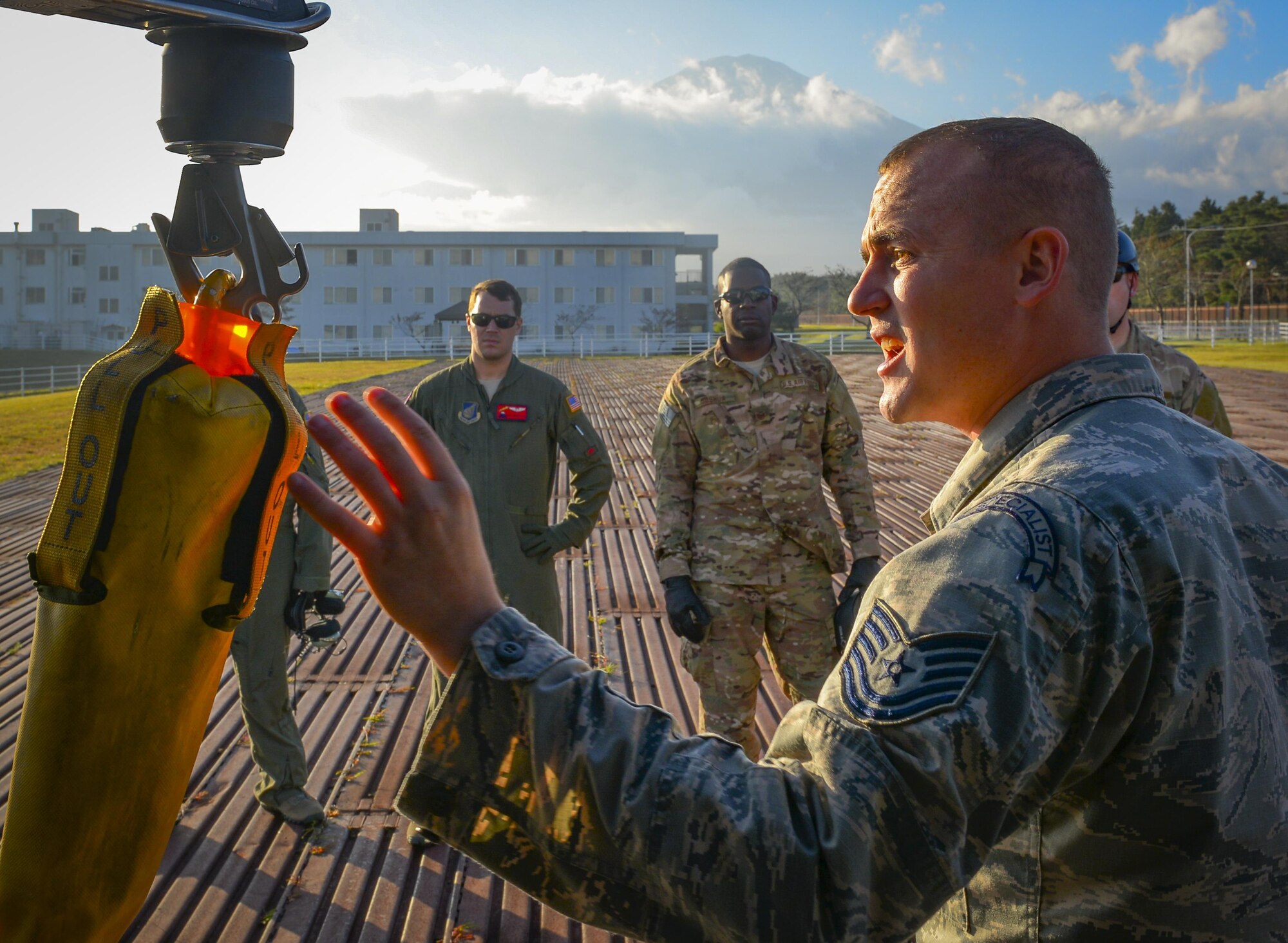 Tech Sgt. Ryan Hyslop, 8th Air Force Detachment Four Survival, Evasion, Resistance and Escape specialist, briefs trainees on how to use a forest penetrator and be hoisted into a helicopter at Camp Fuji, Japan, Oct. 26, 2016. Instructing the trainees is intended to give Hyslop experience that will aid his efforts to construct a SERE program at Anderson Air Force Base, Guam. (U.S. Air Force photo by Airman 1st Class Elizabeth Baker/Released)