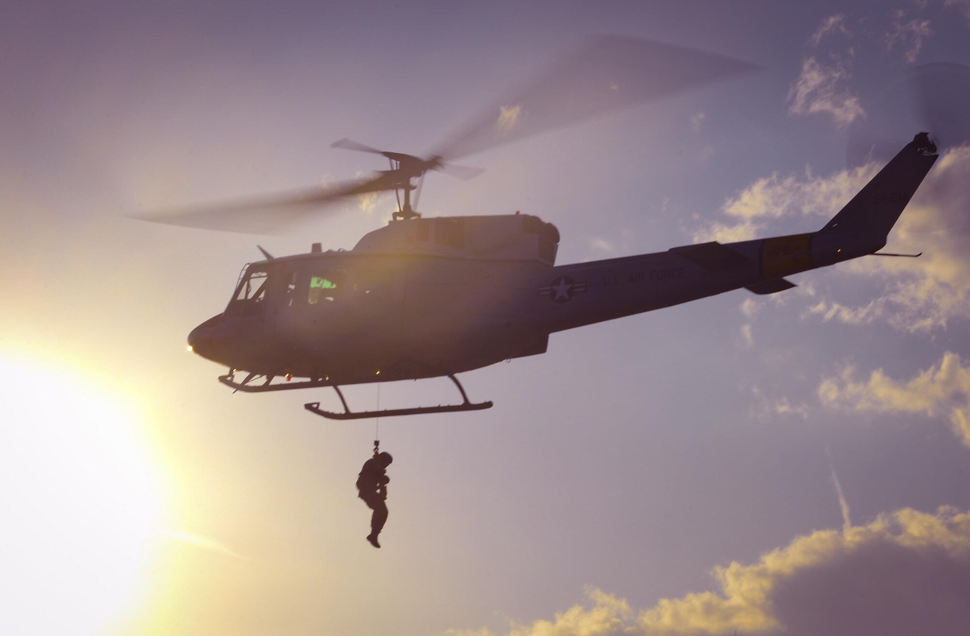 Members of the 459th Airlift Squadron hoist a Survival, Evasion, Resistance and Escape trainee into a UH-1 Iroquois helicopter. SERE personnel maintain hoist qualifications on the forest penetrator rescue seat, a lifesaving device used to hoist personnel in rescue and recovery operations. (U.S. Air Force photo by Airman 1st Class Elizabeth Baker/Released)