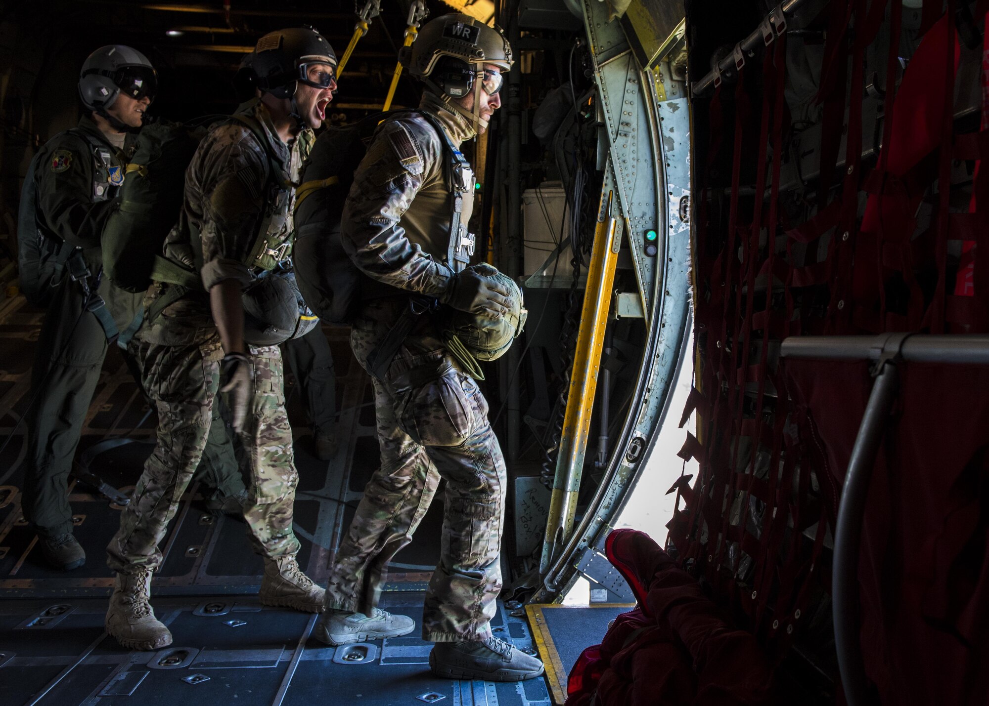 374th Operations Support Squadron survival, evasion, resistance and escape specialists give signals to each other before they perform a static line jump out of a C-130 Hercules 26 Oct. 2016, at Yokota Air Base, Japan. The SERE specialists conduct regular jump training to stay qualified and mission ready.  (U.S. Air Force photo by Airman 1st Class Donald Hudson/Released)