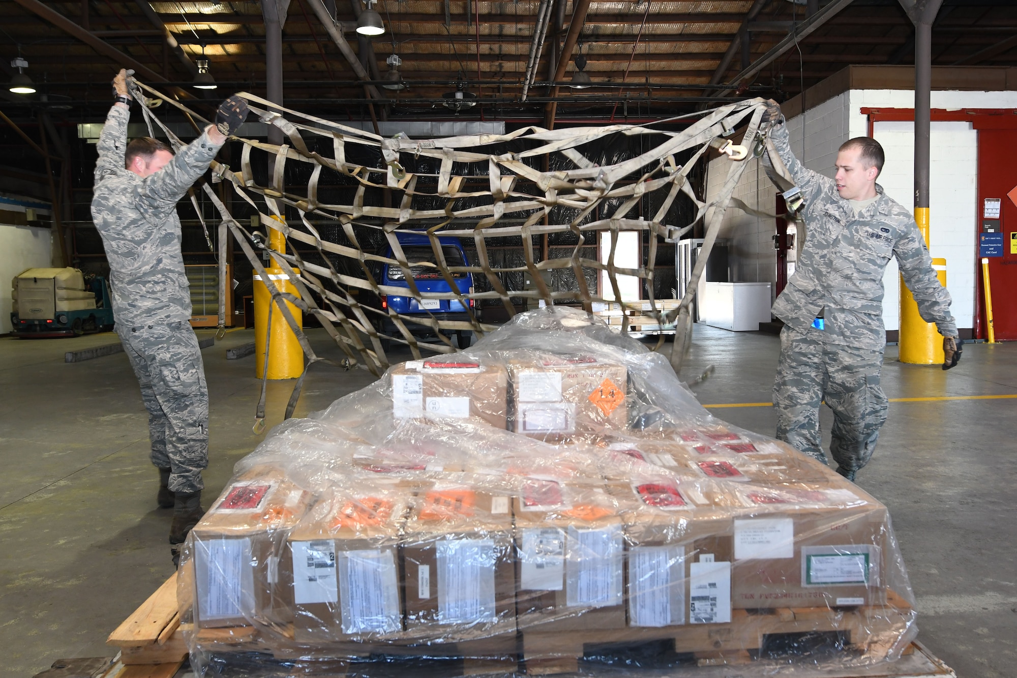 U.S. Air Force Staff Sgt. Richard Allen, 731st Air Mobility Squadron special planning supervisor, and Airman 1st Class Kevin Johnston, 731st AMS special planning technician, toss a securing net over an ammunitions shipping build during routine shipping operations at Osan Air Base, Republic of Korea, Nov. 2, 2016. The special handlers provide storage and shipping requirements for critical military items across the Korean Peninsula. (U.S. Air Force photo by Senior Airman Dillian Bamman)