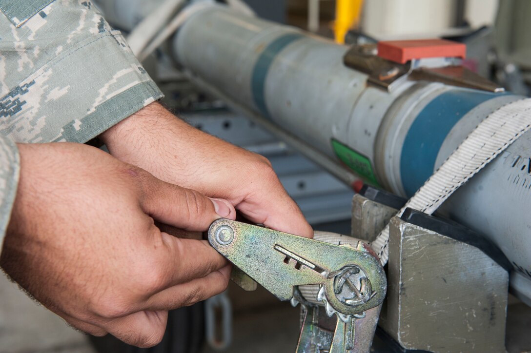 U.S. Air Force Staff Sgt. Nicholas McCants, 44th Aircraft Maintenance Unit load crew chief, secures a ratchet strap during weapons load training Nov. 2, 2016, at Kadena Air Base, Japan. Once every month, load crews conduct weapons load training to maintain proficiency. (U.S. Air Force photo by Senior Airman Lynette M. Rolen/Released)