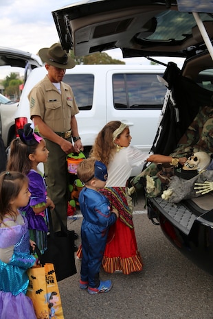 Staff Sergeant Elton G. King, drill instructor, 3rd Recruit Training Battalion, escorts children as they take candy from a trunk during the Marine Corps Community Service’s annual Trunk or Treat event at Marine Corps Recruit Depoit San Diego Oct. 28. Each vehicle had decorations in the trunk and candy for the trick or treaters.