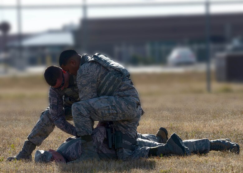 Airman 1st Class Devin Donovan, D’Angelo Monteiro, response force members assigned to the 28th SFS, handcuff Master Sgt. Jason Cast, the first sergeant assigned to the 28th SFS at Ellsworth AFB, S.D., Oct. 27, 2016. Cast was chased down and apprehended as part of a training session simulating an unauthorized entry onto the flightline. (U.S. Air Force photo Illistration by Airman 1st Class Donald Knechtel)