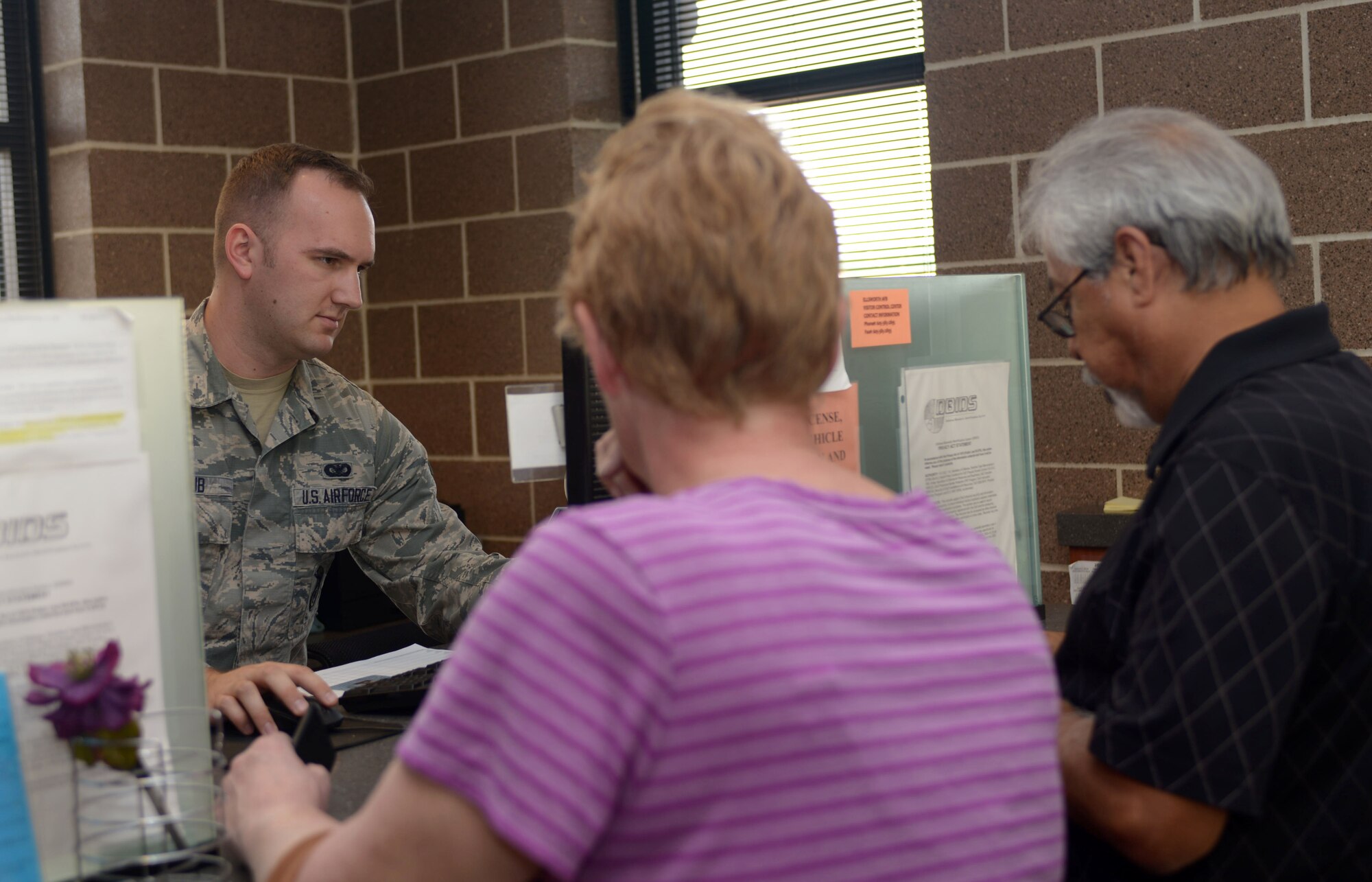 Senior Airman William Shaub, a visitor control center clerk assigned to the 28th Security Forces Squadron, assists a family with base access at Ellsworth AFB, S.D., Oct. 27, 2016. During an average week, the VCC issues approximately 150 paper passes and 80 Department of Defense identification cards to visitors seeking to enter the installation. (U.S. Air Force photo by Airman 1st Class Donald Knechtel)