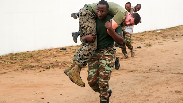 A sailor with the Benin Navy performs the fireman carry with 1st Lt. Joshua Littell, a team leader with Special Purpose Marine Air-Ground Task Force Crisis Response-Africa, during a physical fitness session at Benin Naval Forces Headquarters, Cotonou, Benin, October 25, 2016. The U.S. Marine Corps theater security cooperation team with SPMAGTF-CR-AF spent two weeks teaching an NCO development and maintenance management course during their time training with the Benin Navy.  