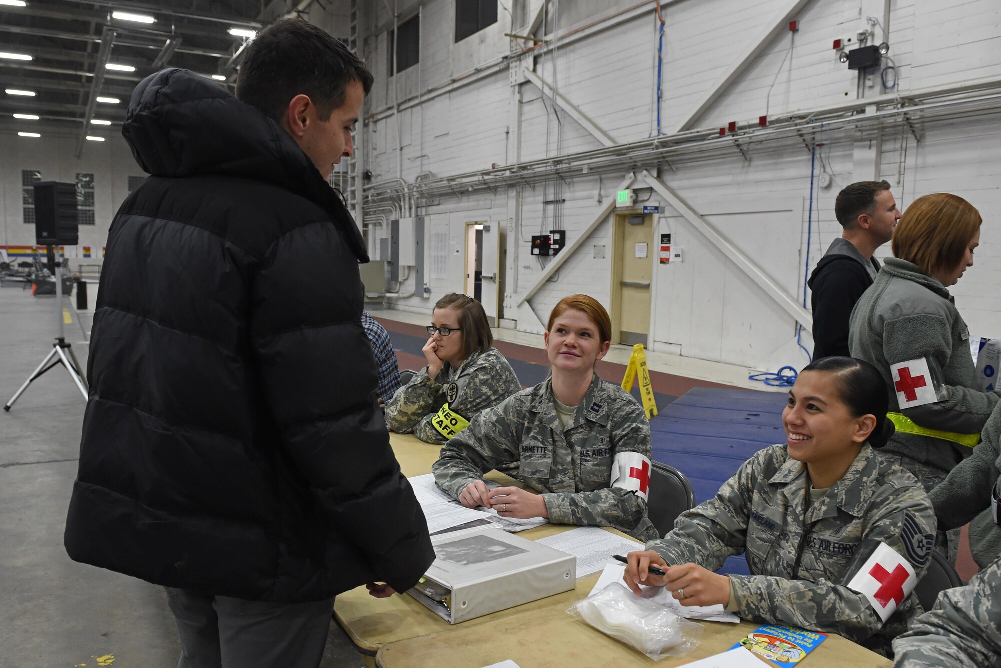 Participants of a noncombatant evacuation operation exercise walk through an in-processing line at Hangar 5, Joint Base Elmendorf-Richardson, Alaska, Nov. 3, 2016. The scenario was part of exercise Polar Force 17-1, which is designed to help validate and evaluate the wings' ability to integrate, mobilize, and prepare assigned personnel, aircraft and equipment for a wartime mission. 