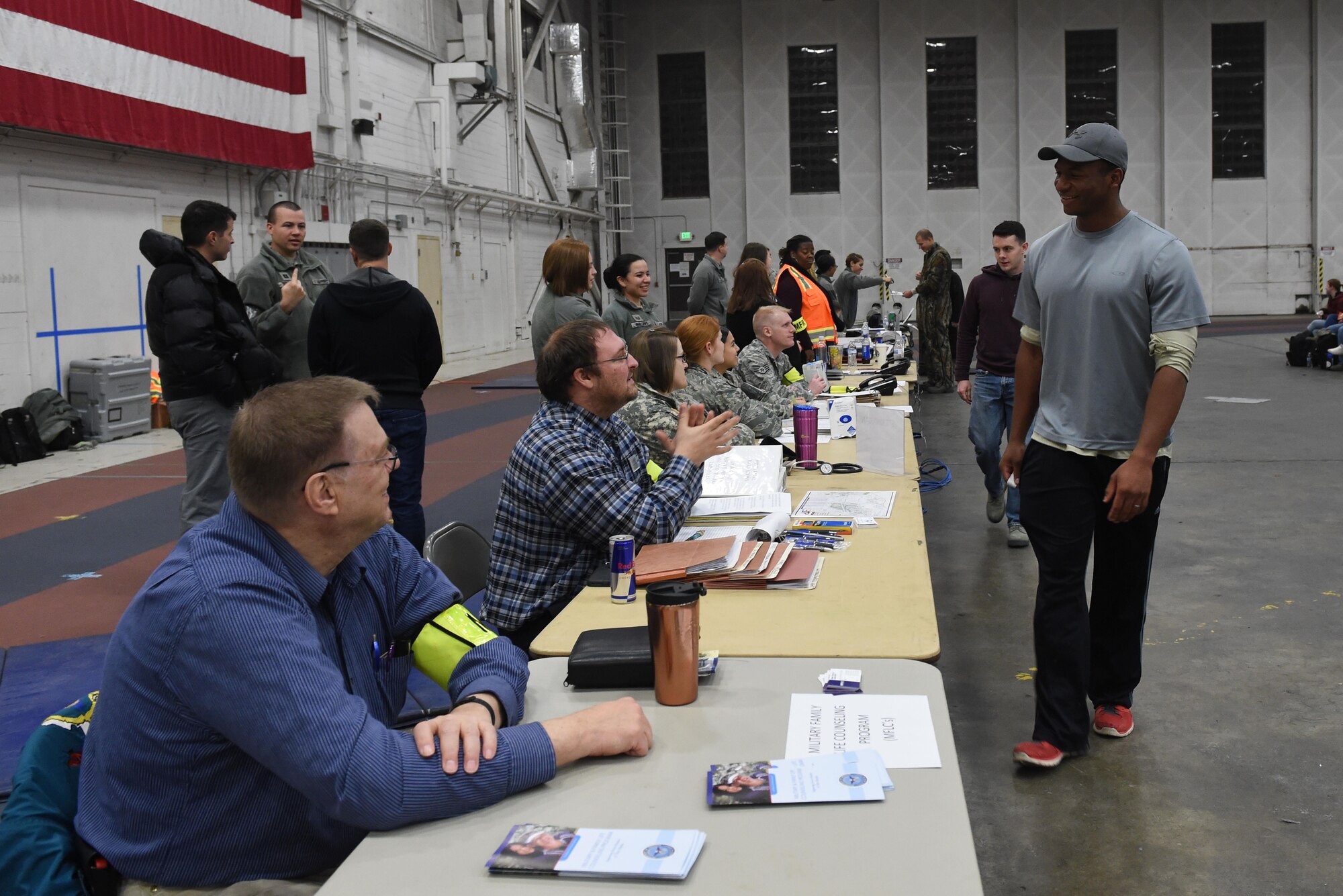 Participants of a noncombatant evacuation operation exercise walk through an in-processing line at Hangar 5, Joint Base Elmendorf-Richardson, Alaska, Nov. 3, 2016. The scenario was part of exercise Polar Force 17-1, which is designed to help validate and evaluate the wings' ability to integrate, mobilize, and prepare assigned personnel, aircraft and equipment for a wartime mission. 