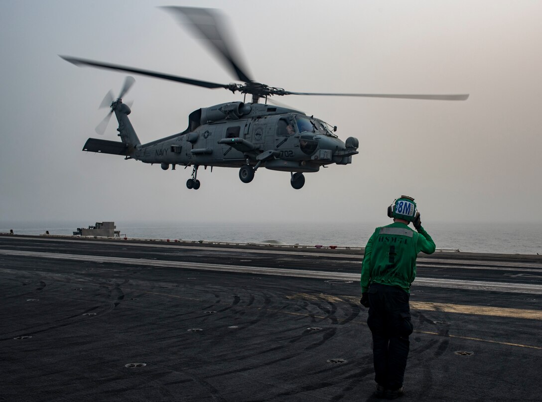 Navy Aviation Structural Mechanic Airman Cammron Jewell salutes an MH-60R Sea Hawk helicopter assigned to the Swamp Foxes of Helicopter Maritime Strike Squadron 74 as it lifts off from the flight deck of the aircraft carrier USS Dwight D. Eisenhower in the Arabian Gulf, Sept. 5, 2016. Navy photo by Petty Officer 3rd Class Nathan T. Beard