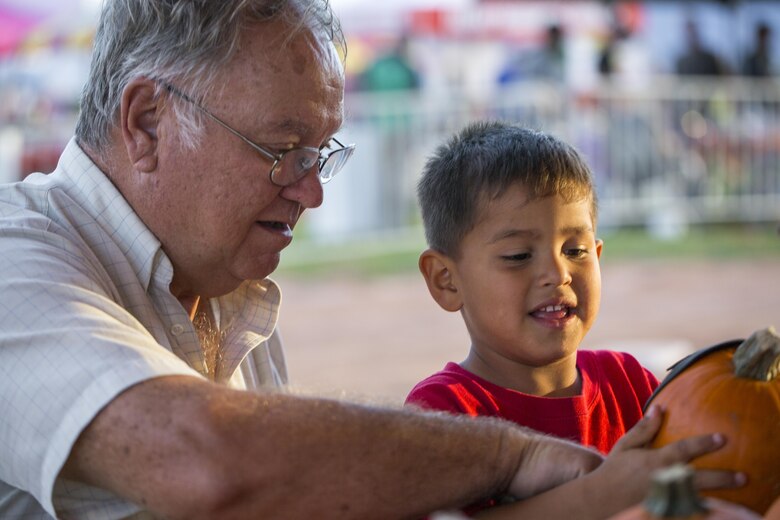Joe Matoush, native of Twentynine Palms, and his grandson Jacob, 4, decorate a pumpkin during the Jack-O-Lantern Jubilee hosted by Marine Corps Community Services at Del Valle Field aboard the Marine Corps Air Ground Combat Center, Twentynine Palms, Calif., Oct. 28, 2016. (Official Marine Corps photo by Cpl. Levi Schultz/Released)