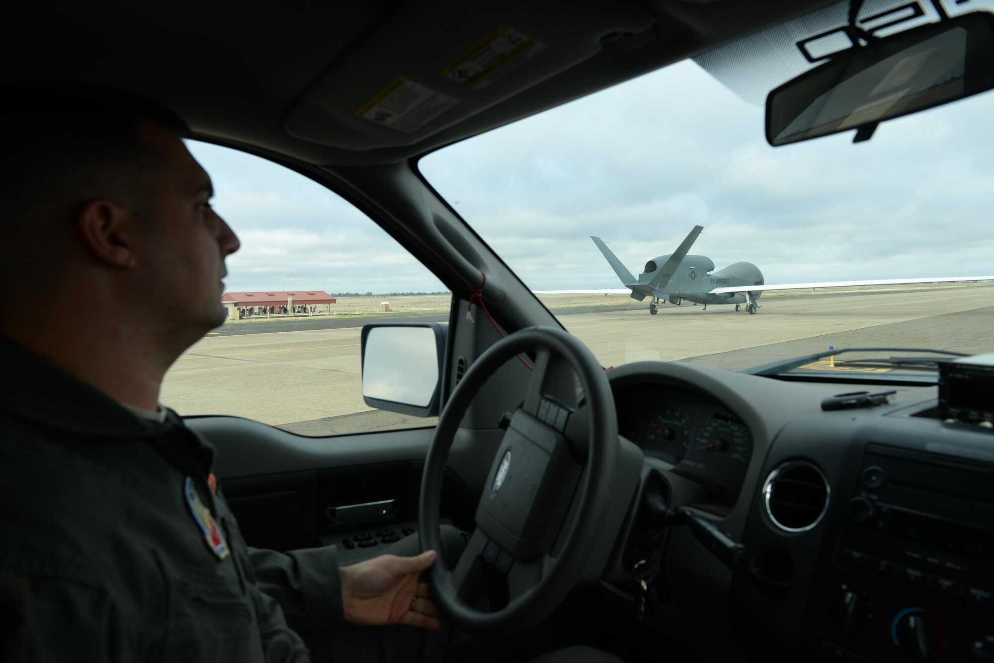Capt. Thomas, 12th Reconnaissance Squadron RQ-4 Global Hawk pilot, follows a RQ-4 Global Hawk down the taxiway Nov. 1, 2016, at Beale Air Force Base, California. Thomas fulfilled the role of “Hawkeye”. Hawkeye serves as the human eyes and ears for the remotely piloted RQ-4 Global Hawk before flight. (U.S. Air Force photo/Staff Sgt. Bobby Cummings)