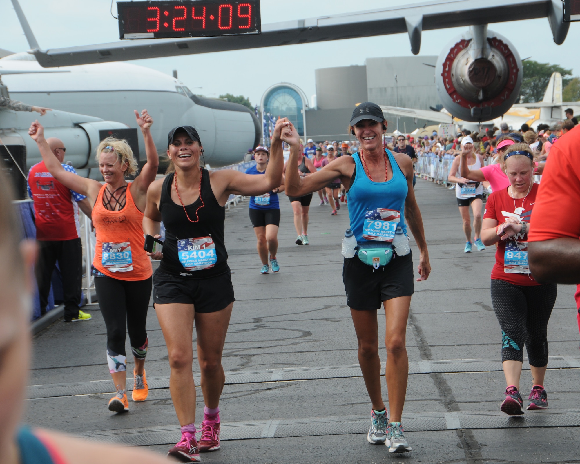 Senior Master Sgt. Kimberly Gunter, center left, and Master Sgt. Kimberly Robertson, center right, both members of the Montana Air National Guard,  hold hands as they cross the finish line at the 20th anniversary U. S. Air Force Marathon at Wright-Patterson Air Force Base, Ohio, Sept. 17, 2016. Gunter, was a first time half-marathon runner participant. (U.S. Air National Guard photo/Staff Sgt. Lindsey Soulsby)