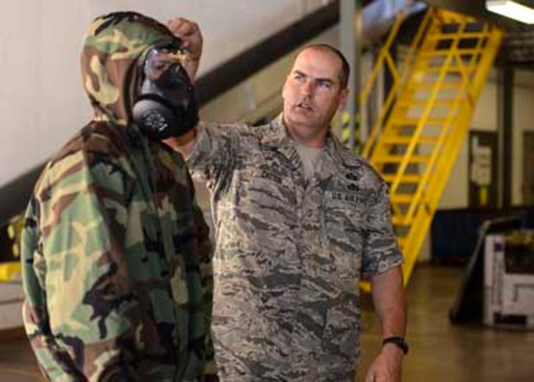 Master Sgt. William Catton, the 189th Airlift Wing emergency management superintendent, instructs Airmen on the proper procedures for donning and checking a protective mask and hood during a chemical, biological, radiological or nuclear training session. The class is a requirement for all Air National Guard members regardless of their mobility status, and is required every three years.(U.S. Air National Guard photo by Tech. Sgt. Jessica Condit) 