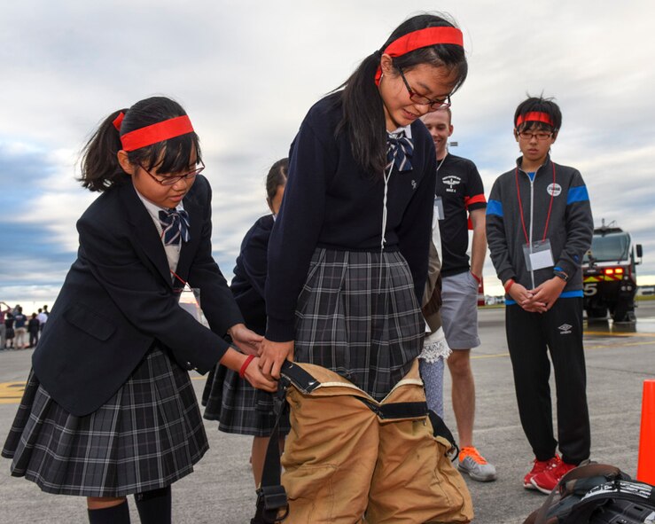 Attendees wear a firefighter suit during the Youth international Exchange Fair at Yokota Air Base, Japan, Oct. 29, 2016. The fair hosted by the Yokota Company Grade Officers Council and Junior Chamber International Japan to foster interaction between Japanese and Yokota children. Approximately thirty students from Yokota and Tachikawa, Japan participated in the event, included a base tour, a workshop on the United Nation Global Goals for Sustainable Development and trick‐or-treating. (U.S. Air Force photo by Machiko Arita/Released)