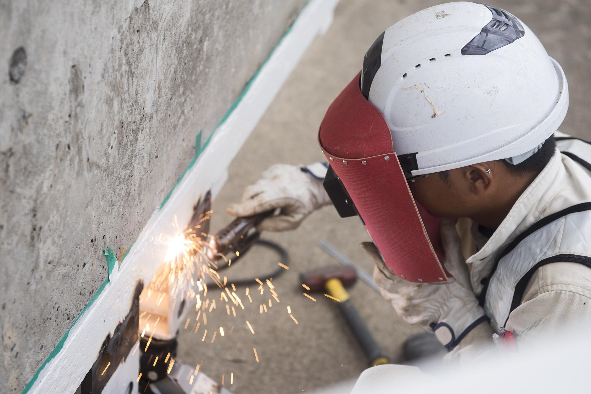 A construction worker welds a hangar door that is being replaced Nov. 1, 2016, at Kadena Air Base, Japan. In an environment where the air is humid and salty, rust plays a factor in every day maintenance so extra work helps ensure buildings are functional and mission ready. (U.S. Air Force photo by Airman 1st Class Corey M. Pettis/Released)