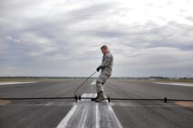 U.S. Air Force Staff Sgt. Ryan Albert, 100th Civil Engineer Squadron power production craftsman, adjusts a barrier cable Oct. 28, 2016, on RAF Mildenhall, England. For optimum performance, the cable needs to be properly aligned and tied down to catch aircraft. (U.S. Air Force photo by Senior Airman Christine Halan)