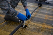A U.S. Air Force Airman from the 100th Civil Engineer Squadron power production shop ties down a Mobile Aircraft Arresting System cable Oct. 28, 2016, on RAF Mildenhall, England. For optimum performance, the cable needs to be properly aligned and tied down to catch aircraft. (U.S Air Force photo by Senior Airman Christine Halan)