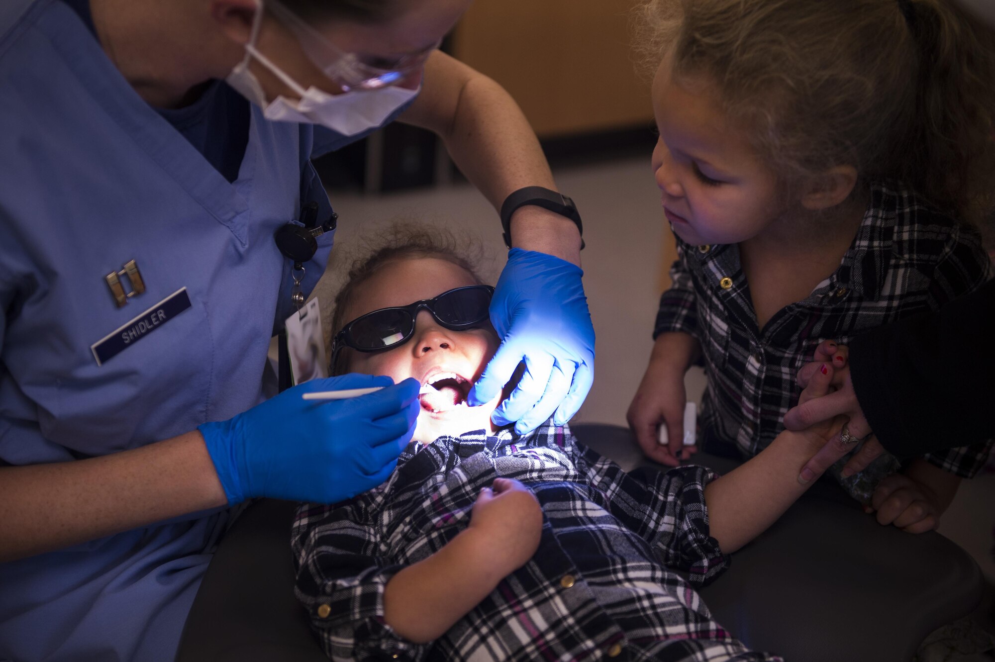 Zian Riley, 2, daughter of Staff Sgt. Ryan Riley, 52nd Communications Squadron inspector manager, receives an oral exam while her older sister looks on during the 52nd Dental Squadron’s semi-annual walk-in kiddie clinic at Spangdahlem Air Base, Germany, Nov. 4, 2016. Dentists educated parents and children on proper oral hygiene to fight cavities and gingivitis in addition to providing normal oral checkups. (U.S. Air Force photo by Senior Airman Dawn M. Weber)