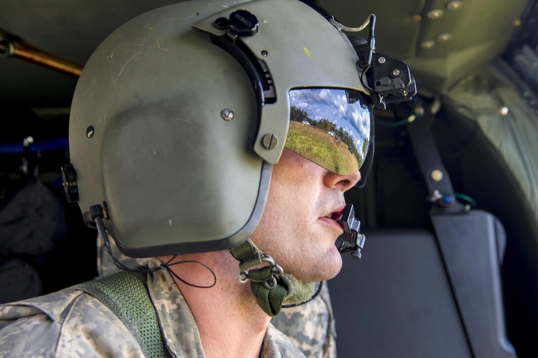 Army Sgt. Bradon Smith watches as Army Special Forces soldiers perform a medical evacuation during Southern Strike 17 at the Gulfport Combat Readiness Training Center, Miss., Oct. 26, 2017. Smith is a crew chief assigned to the Mississippi Army National Guard’s Golf Company, 1st Battalion, 168th Aviation Regiment. Air Force photo by Airman 1st Class Sean Carnes 