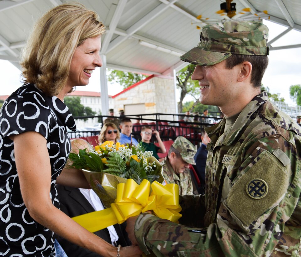 1st Lt. Matthew Wilkerson presents a bouquet of yellow roses to Brig. Gen. Alex Fink's wife, Mrs. Janet Fink, welcoming her into the 4th Sustainment Command (Expeditionary) family during the unit's change of command ceremony held at Fort Sam Houston, Texas, on Oct. 15, 2016.  (U.S. Army Photo by Spc. Eddie Serra).