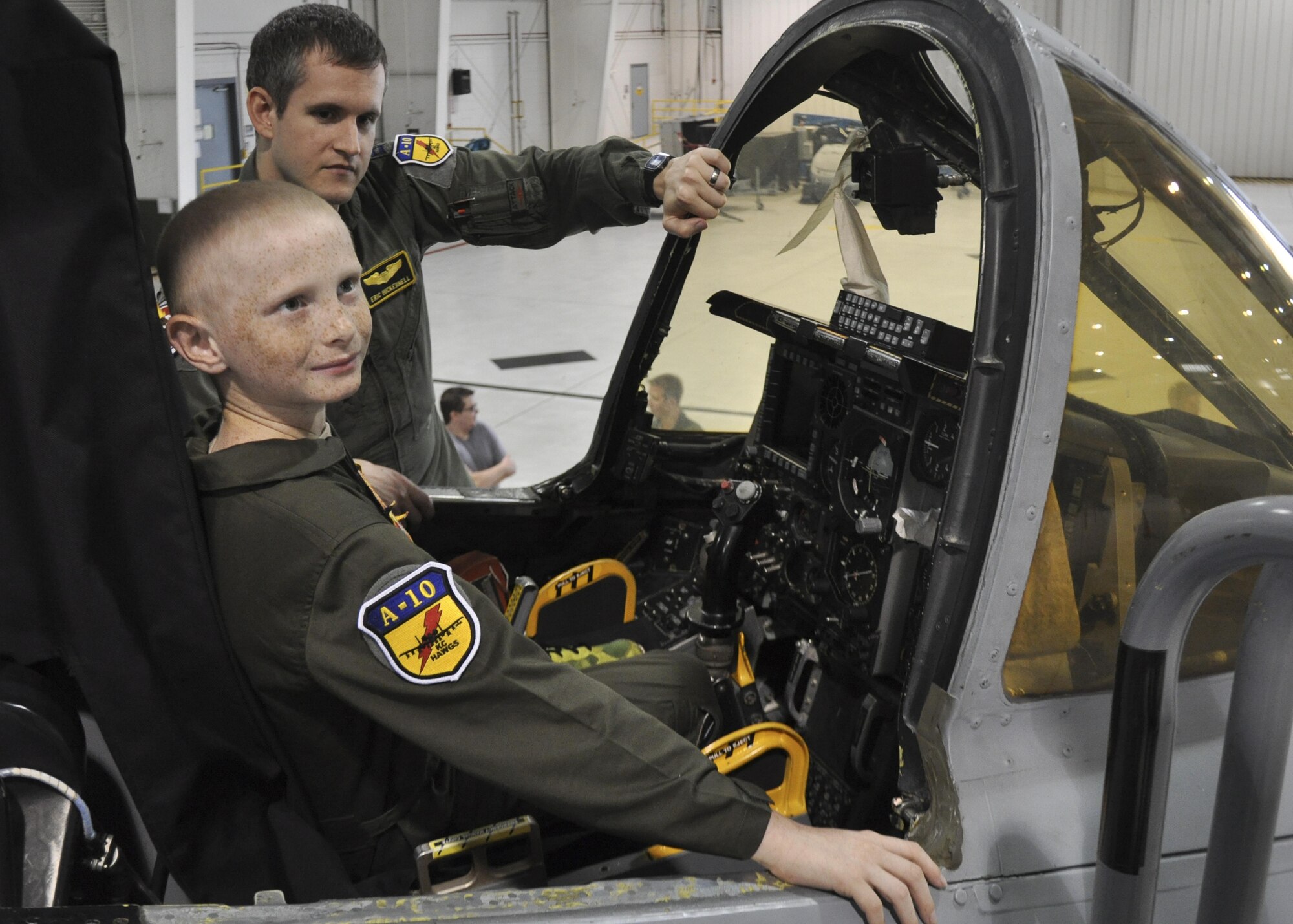 Britton Whiteside, honorary "pilot of the day," smiles at his dad while he sits in the cockpit of an A-10 Thunderbolt II at Whiteman Air Force Base, Mo., November 3, 2016. Britton was presented patches and a 303rd Fighter Squadron morale T-shirt to complete his pilot uniform. (U.S. Air Force photo/Senior Airman Missy Sterling)