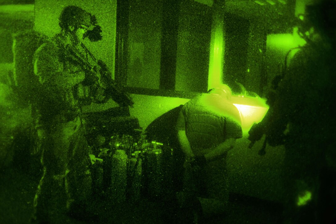 As seen through a night-vision device, Army Special Forces and Air Force special operations forces personnel guard a role playing high value target during room clearing and close quarters battle operations, part of Southern Strike 17 at Naval Station Pascagoula, Miss., Oct. 26, 2016. Air Force photo by Tech. Sgt. Gregory Brook