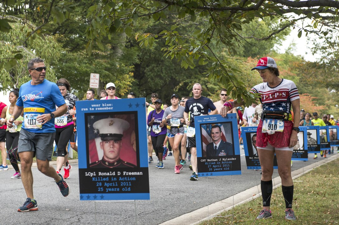 A runner pauses for a moment of reflection during the Marine Corps Marathon in Washington, D.C., Oct. 30, 2016. The posters were a part of the Wear Blue Mile, which honored troops lost during service to their country. Marine Corps photo by Lance Cpl. Timothy Smithers