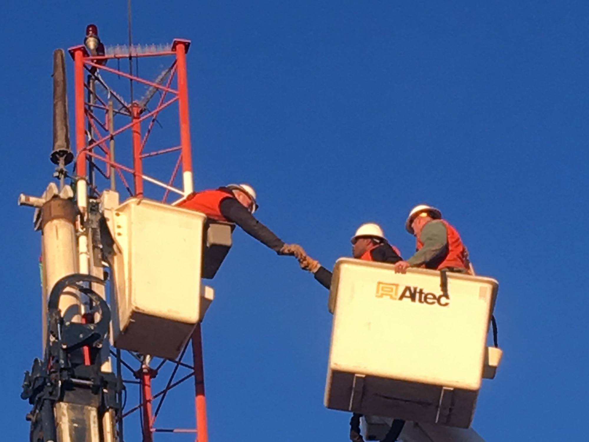 U.S. Air Force Airmen from the 354th Civil Engineer Squadron pass a tool to each other Oct. 6, 2016, at Eielson Air Force Base, Alaska. They removed the top 10 feet of an antenna mast so that it may be reused at another location. (U.S. Air Force photo by Master Sgt. Jennifer Brown)