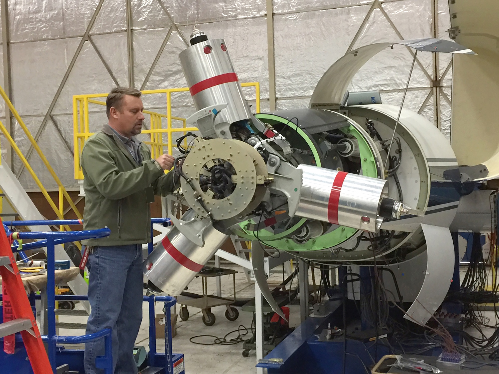 AEDC instrumentation engineer Dan Pruyn works on the Tiltrotor Test Rig in preparation for a test in the 40-foot by-80-foot wind tunnel at the National Full-Scale Aerodynamics Complex, the AEDC wind tunnel testing site located in California. The test of the TTR is a project sponsored by the National Aeronautics and Space Administration. TTR is a horizontal axis rig and rotates on the test section turntable to face the rotor into the wind at high speed, or fly edge-wise at low speed (100 knots), or at any angle in between. It is designed to accommodate a variety of rotors. (U.S. Air Force photo/Jeffrey Johnson)