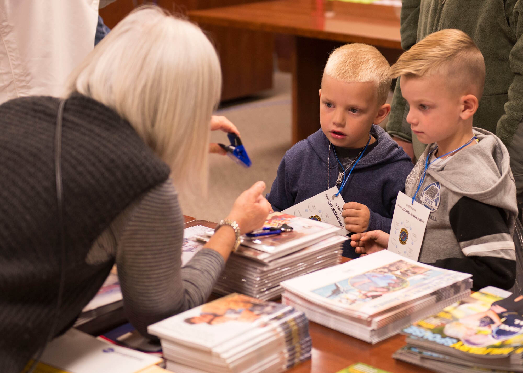 A representative from the Airman and Family Readiness Center gives two boys a paper clip at the Kids Understanding Deployment Operations day Oct. 21, 2016, at Mountain Home Air Force Base, Idaho. The children also received coloring books and other treats in their gift bags. (U.S. Air Force photo by Airman Jeremy D. Wolff/Released)