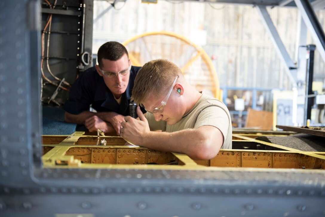 U.S. Air Force Senior Airman Caleb Kerbo and Staff Sgt. Joseph Ogorek, 18th Equipment Maintenance Squadron aircraft structural maintenance technicians, find and repair corrosion on the belly of a Pavehawk during a phase inspection Nov. 3, 2016, at Kadena Air Base, Japan. Multiple maintenance agencies across Kadena work together during a phase inspection. (U.S. Air Force photo by Senior Airman Omari Bernard/Released)