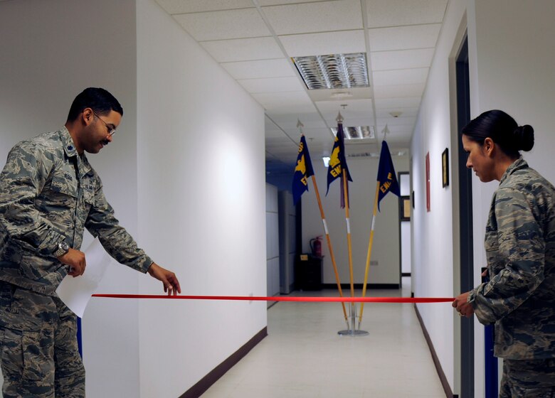 U.S.Air Force Lt.Col. Ramon Veglio,the medical logistics and readiness flight commander,left,and Lt. Col. Stella Garcia,the 379th Expeditionary MedicalSupport Squadron commander,both with the 379th Expeditionary Medical Group,hang the ribbon for a ribbon cutting ceremony to open the new medical administration building at AI Udeid Air Base,Qatar,Nov. 2,2016.The expansion to the 379th EMDG will allow for apheresis,mental health,biomedical equipment repair and bioenvironmental engineering to be housed in one facility.(U.S.Air Force photo by Senior Airman Cynthia A.Innocenti)